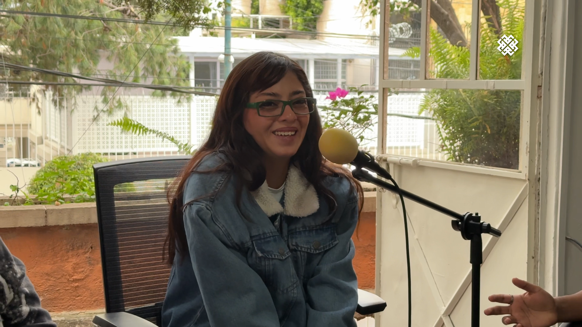 Primer plano de Cachirula, integrante de Cachirula & Loojan, sonriendo y hablando frente a un micrófono durante la entrevista sobre 'Sexolandia' y Coachella.