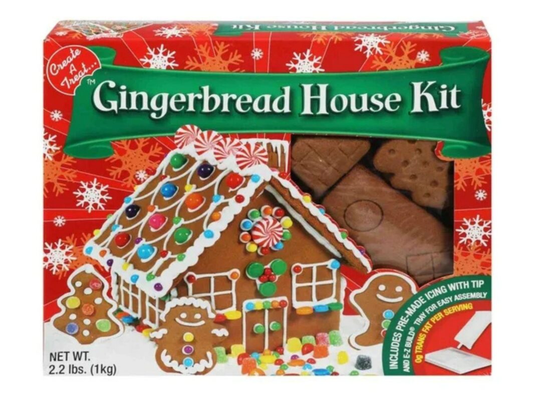 Kit de casita de jengibre de la marca Kirkland Signature de Costco, decorada con dulces y glaseado blanco sobre una mesa navideña.