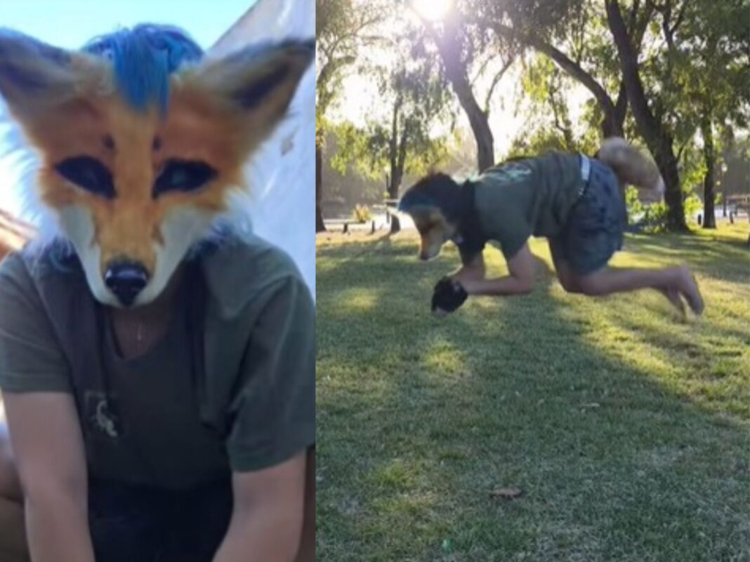 Lexi, joven que se identifica como zorro, caminando por un sendero boscoso con su máscara característica.