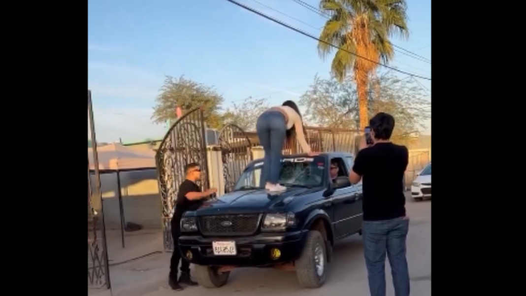 Mujer parada sobre el cofre de una camioneta negra pateando el parabrisas durante una discusión en Chihuahua.