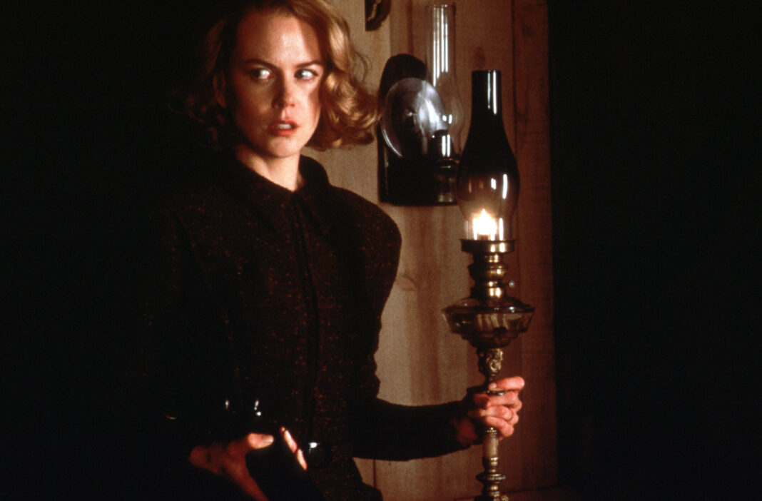 Nicole Kidman sostiene una lámpara en una escena oscura de la película Los otros.